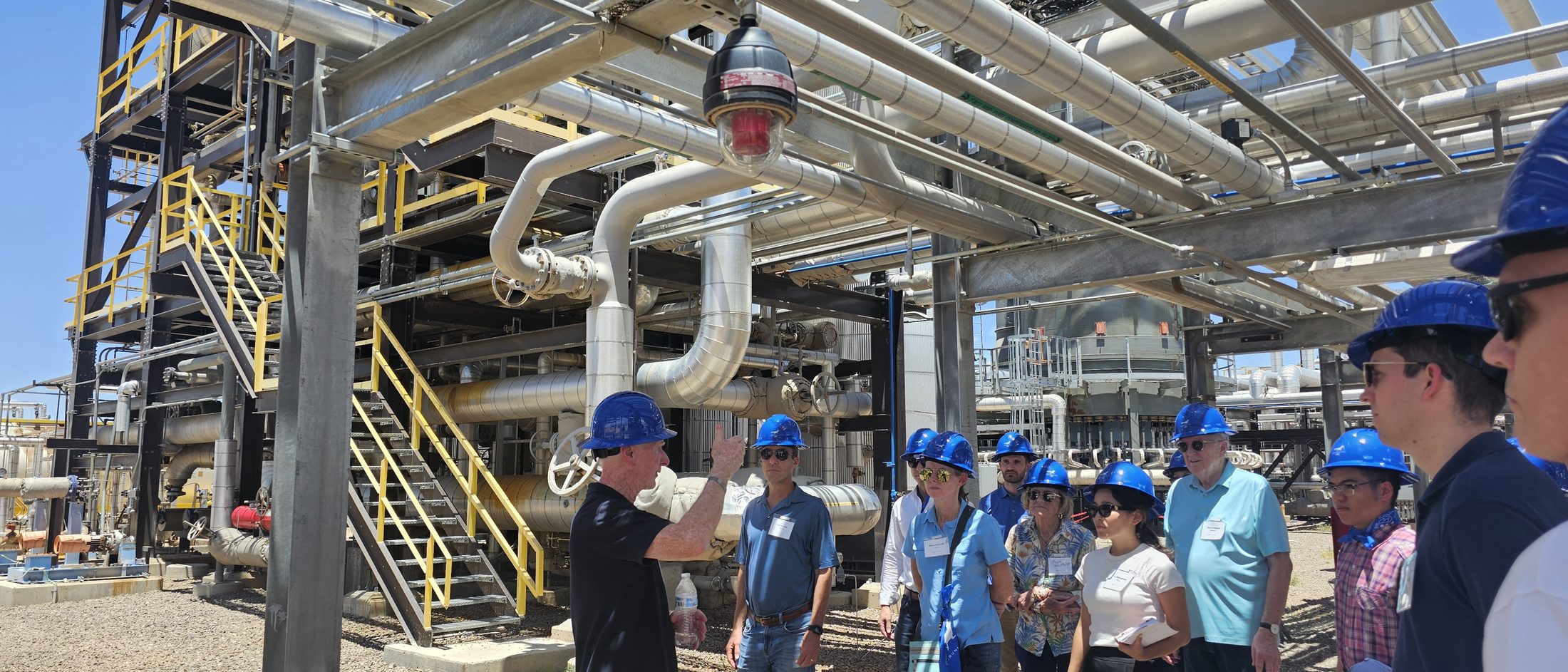 Infinium engineers walking visitors in hard hats through the process racks of a West Texas eFuels facility